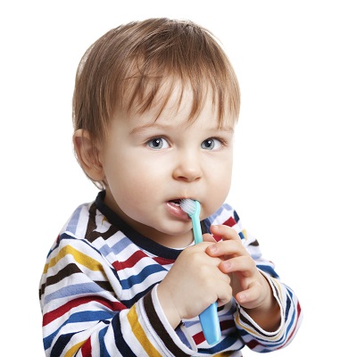 Baby in striped shirt holding a toothbrush in mouth at Tiny Teeth Pediatric Dentistry.